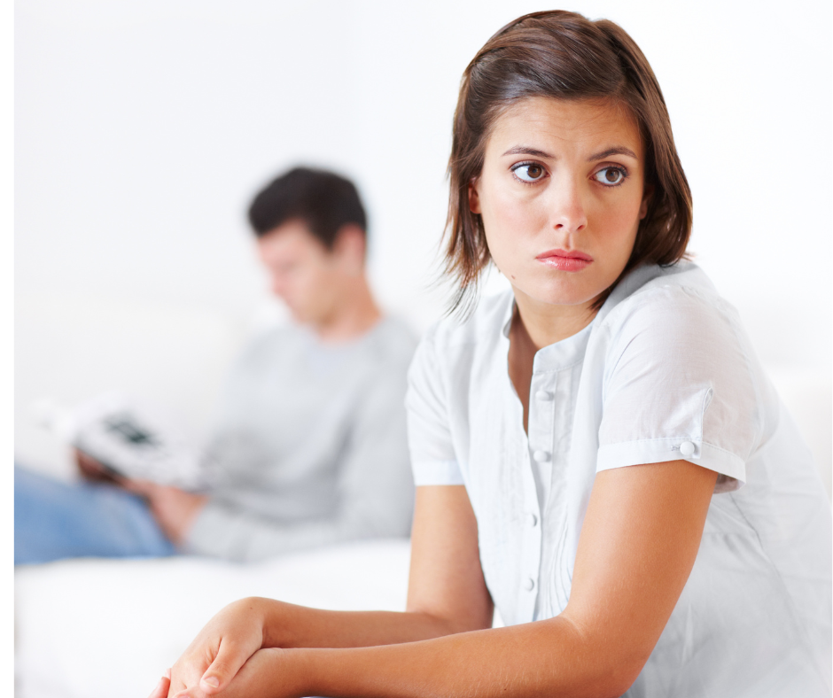 How to deal with unpleasant emotions. A photo of a woman looking sad while a man looking at his phone is sitting in the background.