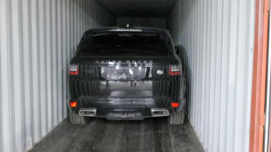 A Range Rover sitting in a shipping container.