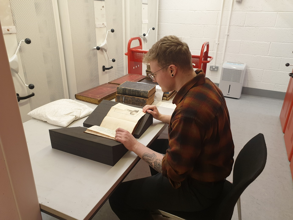 Connor at a desk examining a book from the Special Collections