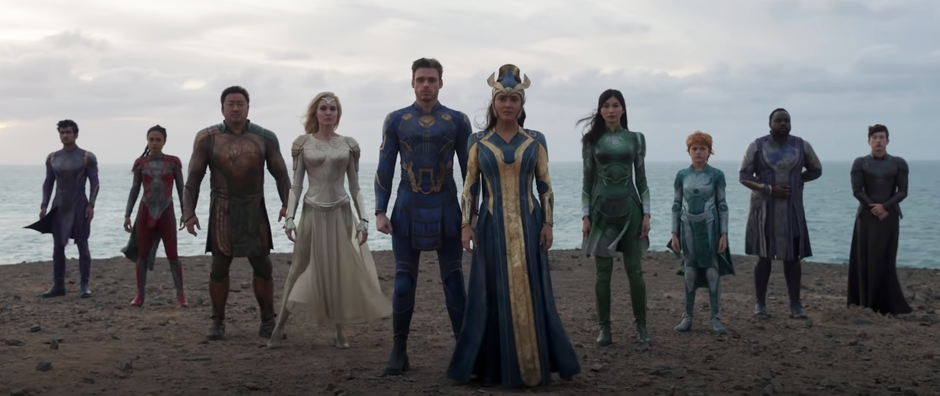 The cast of Eternals (2021) standing on a beach.