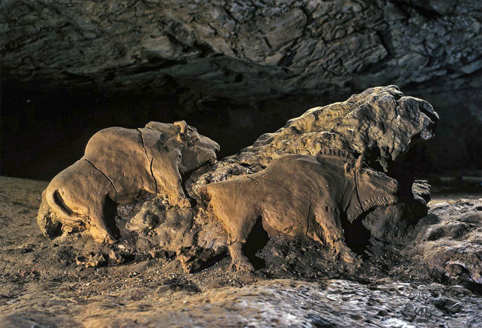 A rock in a cave, with two bison sculpted in clay sitting proud of the rock