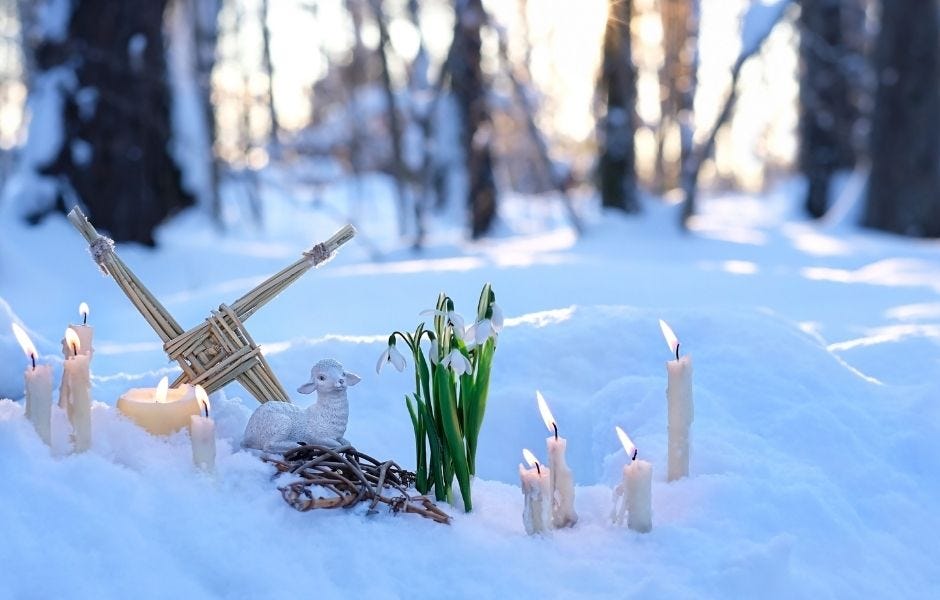 Imbolc Brigid’s cross outside in snow with flowers and candle