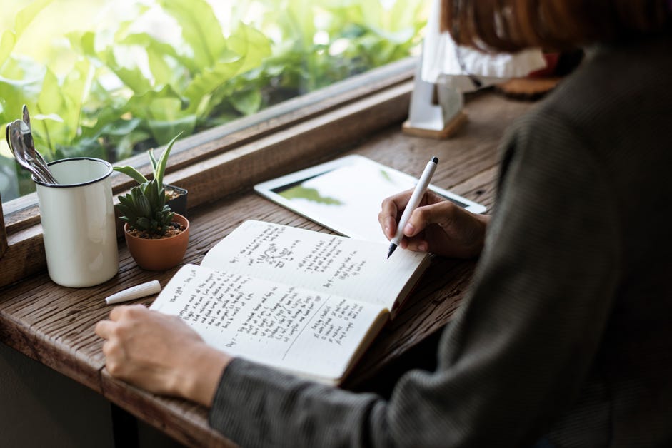 writing in journal by window
