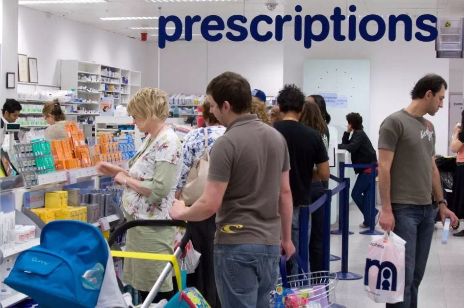 A busy pharmacy with many customers queuing at the front counter, as well as people browsing nearby.