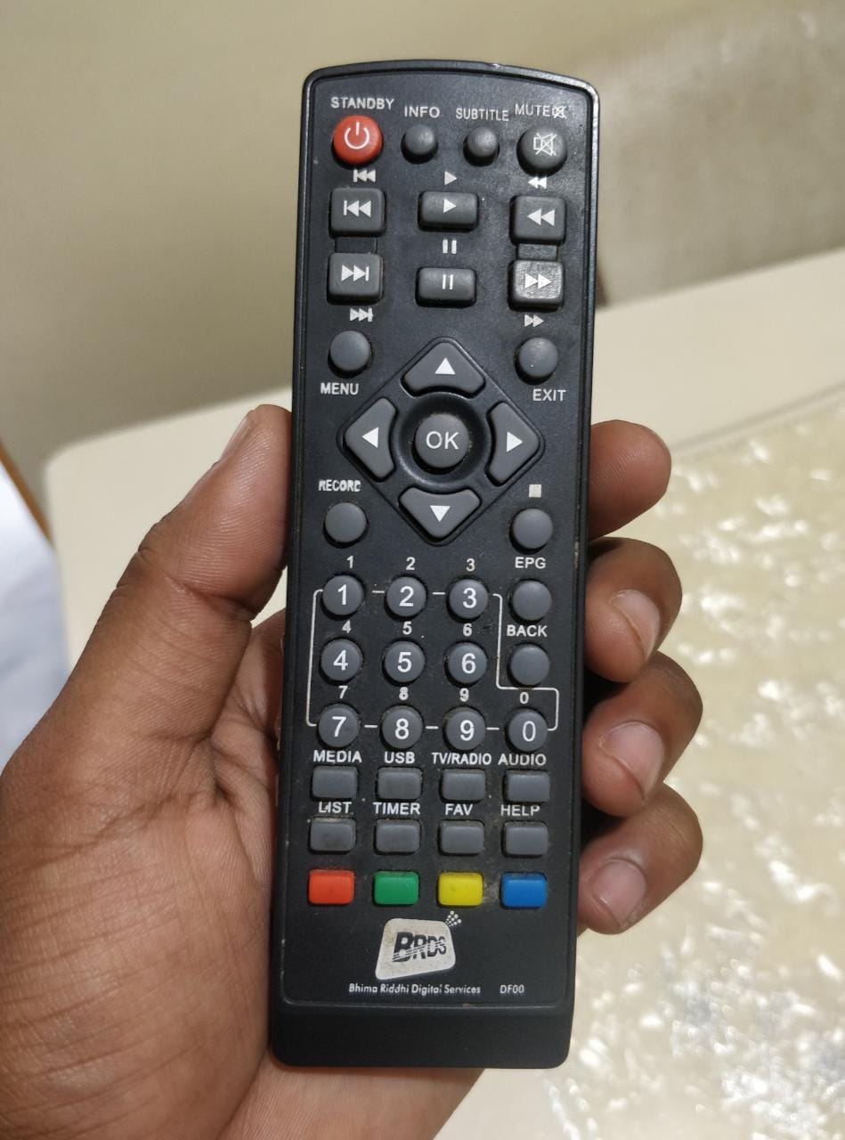 a set top box remote held in a hand.