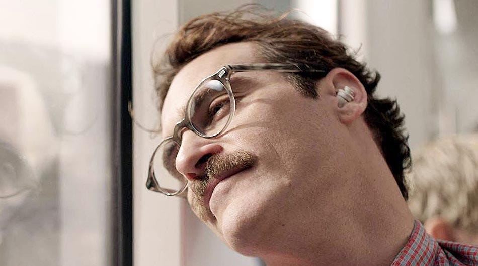 A imagem mostra o ator Joaquin Phoenix no filme Her, ele expressa um leve sorriso enquanto olha pela janela