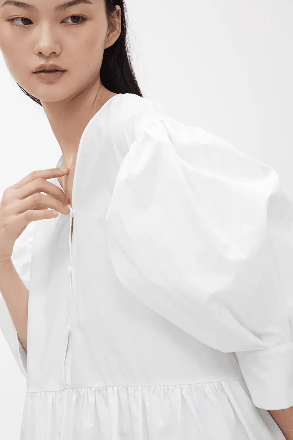 Model poses in white puff-sleeved blouse