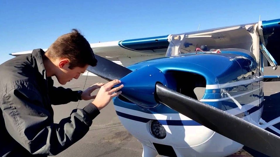 Photo of pilot inspecting a propeller.