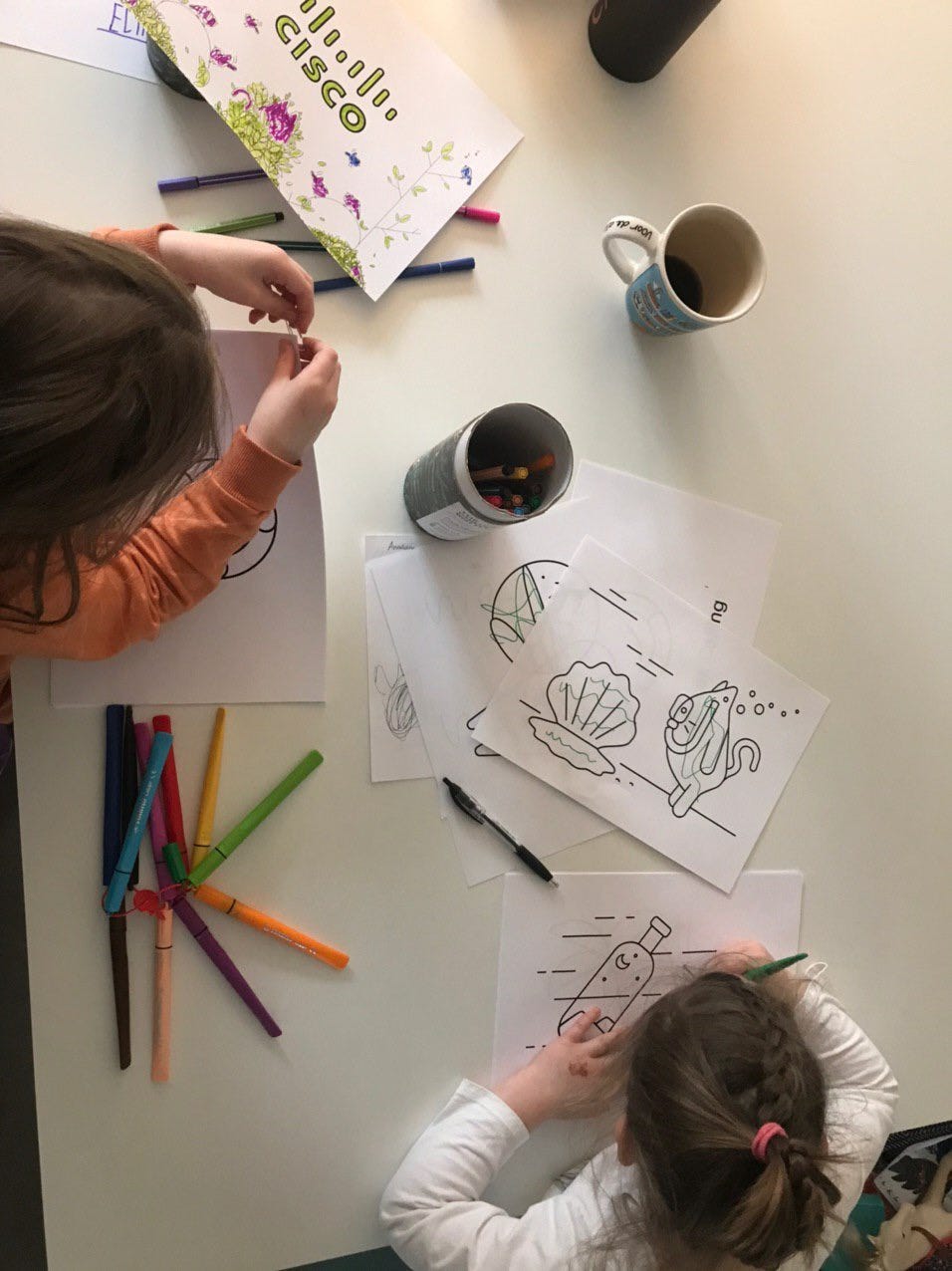 An overhead view of two children colouring in their pages