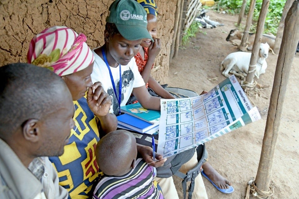 A Graduating to Resilience Coach reviewing the household plan with a couple at their home during a coaching session. (Photo: AVSI Foundation)