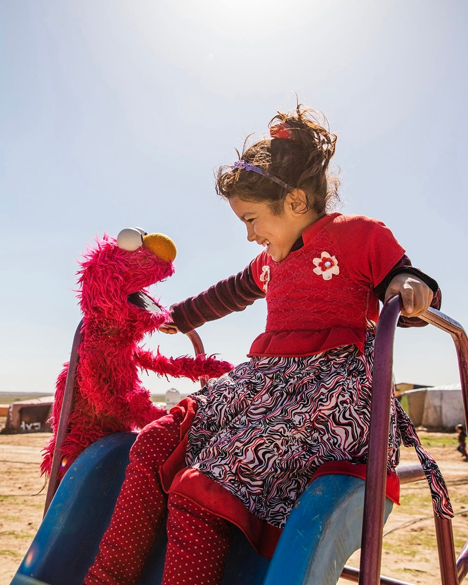 A young girl plays with Elmo
