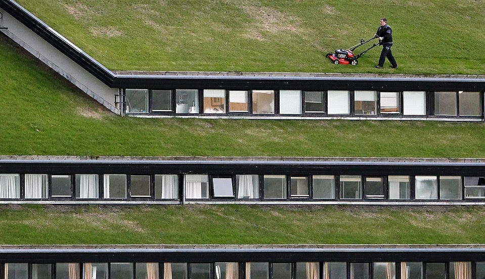 A person mowing a roof lawn on a multi level building