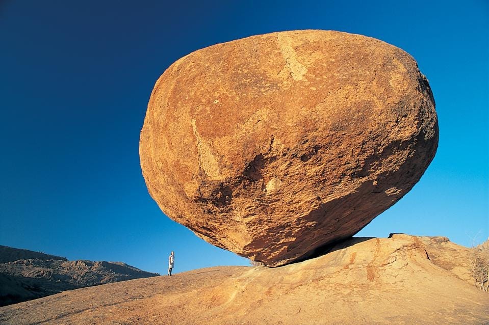 photo of large rock dwarfing a person