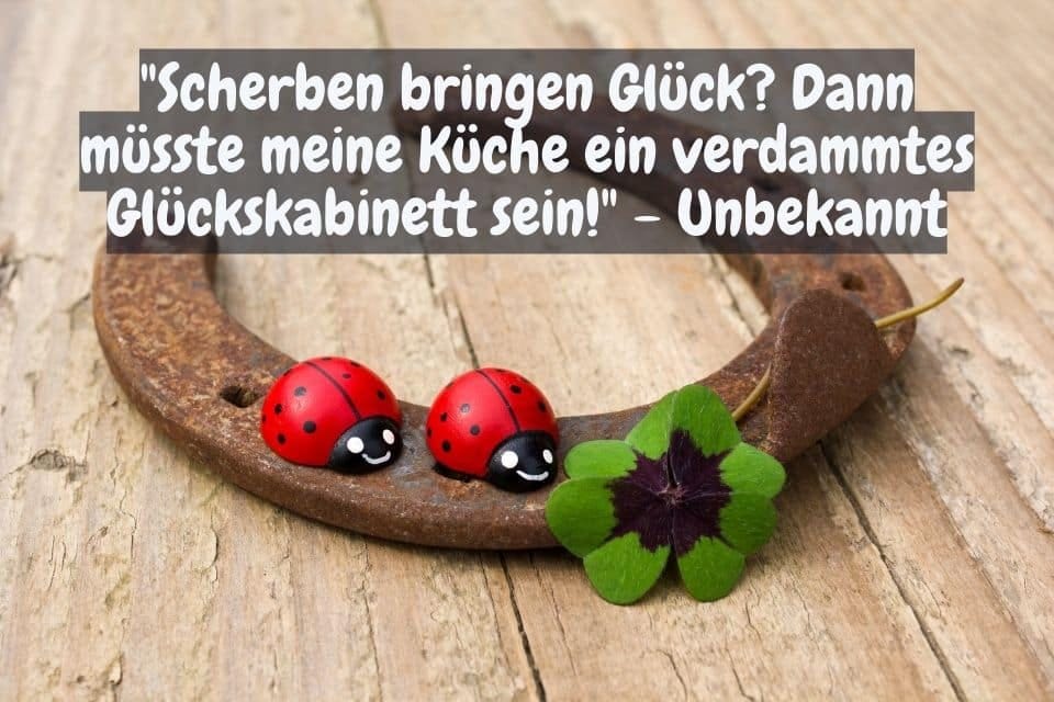 Ein Hufeisen liegt auf einem Holztisch, dekoriert mit zwei Marienkäfern und einem Kleeblatt. Darüber steht der humorvolle Text: