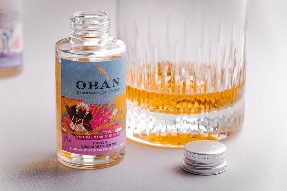 A photograph of a small bottle of Oban whisky next to a glass of whisky.