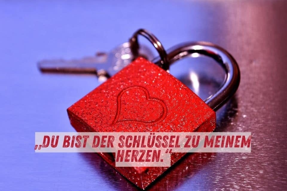 Das Bild zeigt ein rotes Vorhängeschloss mit einem eingravierten Herz, daneben liegt ein Schlüssel. Der Hintergrund ist blau und metallisch. Unten im Bild steht der Text: