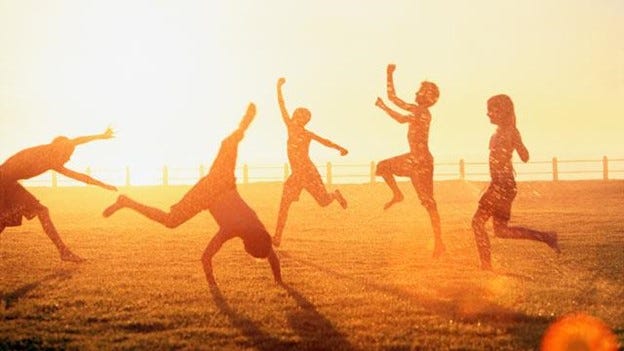 Silhouette of 5 kids having fun at a beach during summer