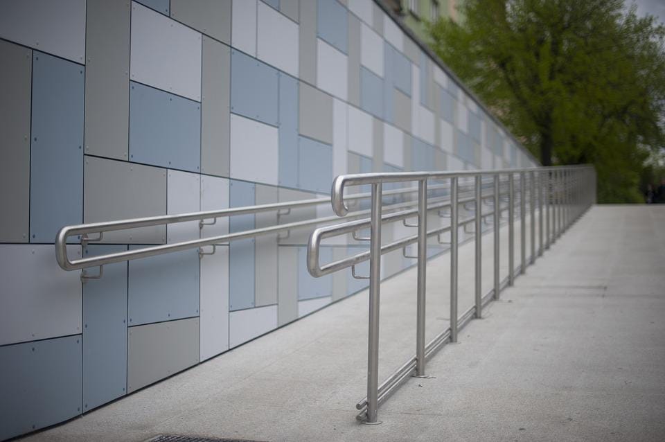 A concrete ramp with a metal railing next to a tiled wall