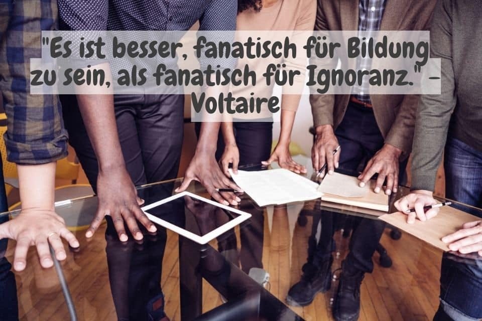 Das Bild zeigt eine diverse Gruppe von Menschen, die um einen Glastisch stehen. Ihre Hände liegen auf Dokumenten, einem Notizbuch und einem Tablet auf dem Tisch. Oben steht das Zitat: