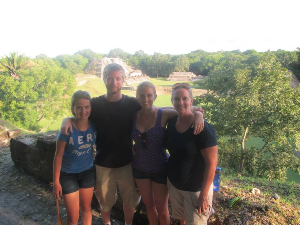 Author with her family posing in front the grassy field and Mayan structures.