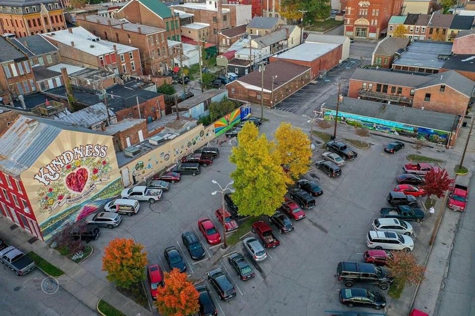 A drone capture of the Kindness mural, standing largely over a parking lot in the Fall with trees of orange and yellow.