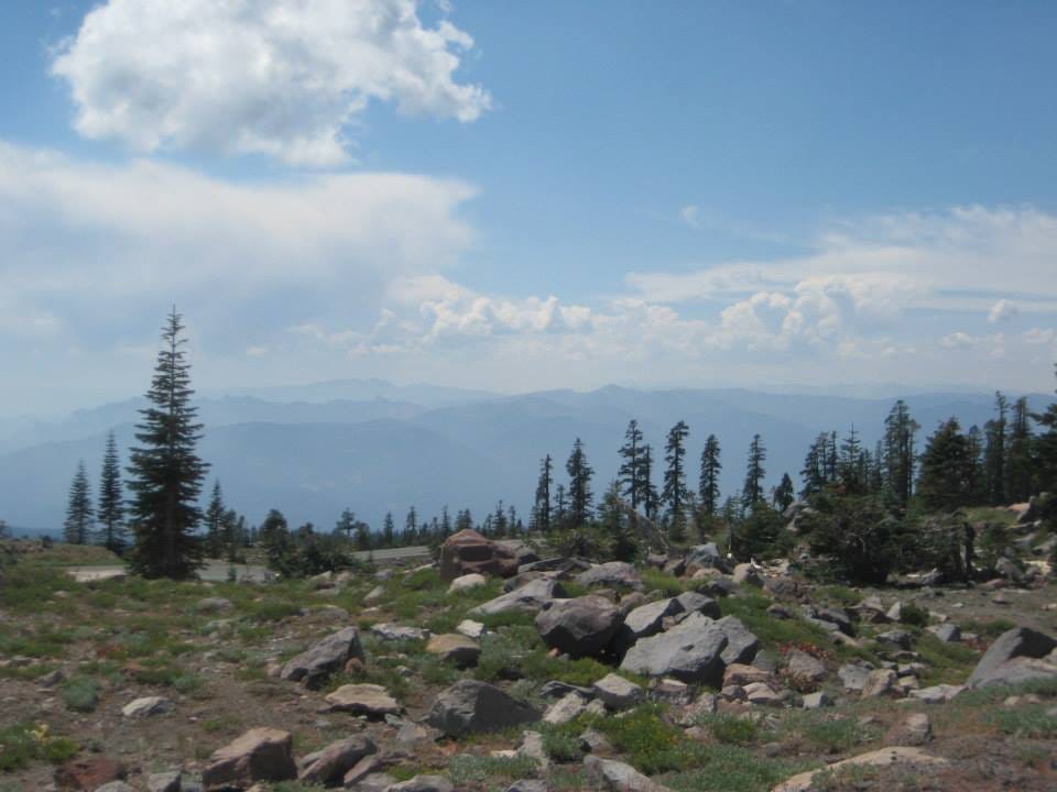 A view of the mountains, trees, rocks, sky, and clouds from upon Mount Shasta, California