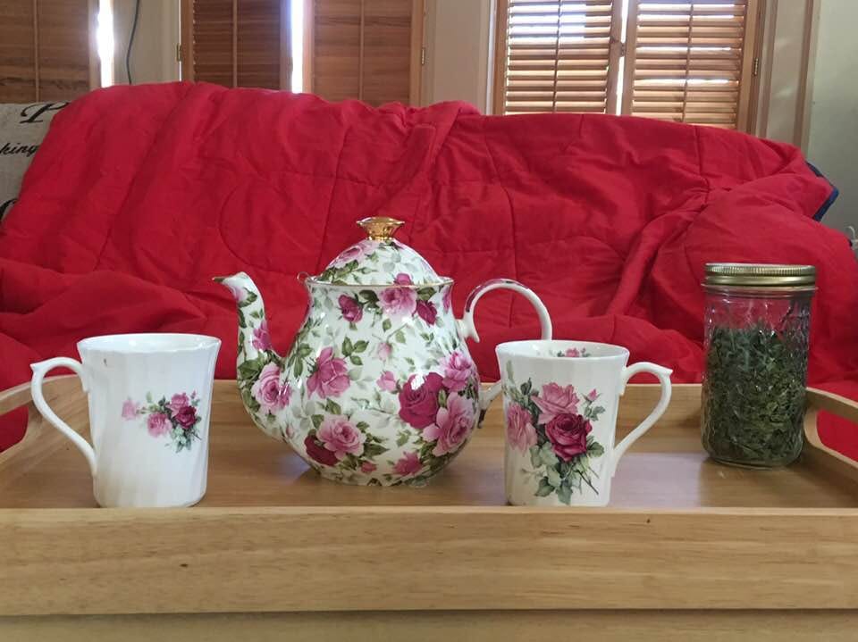 A tray with floral china cups and a china teapot in front of a couch