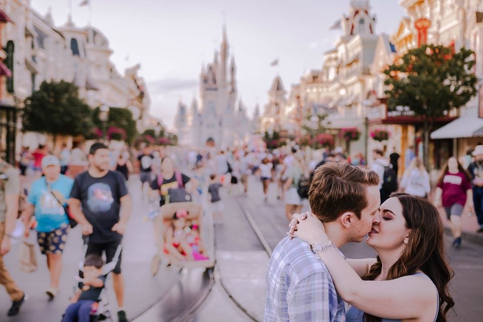Photo of couple kissing in front of Cinderella’s Castle in Disney World, by Wildly Wed