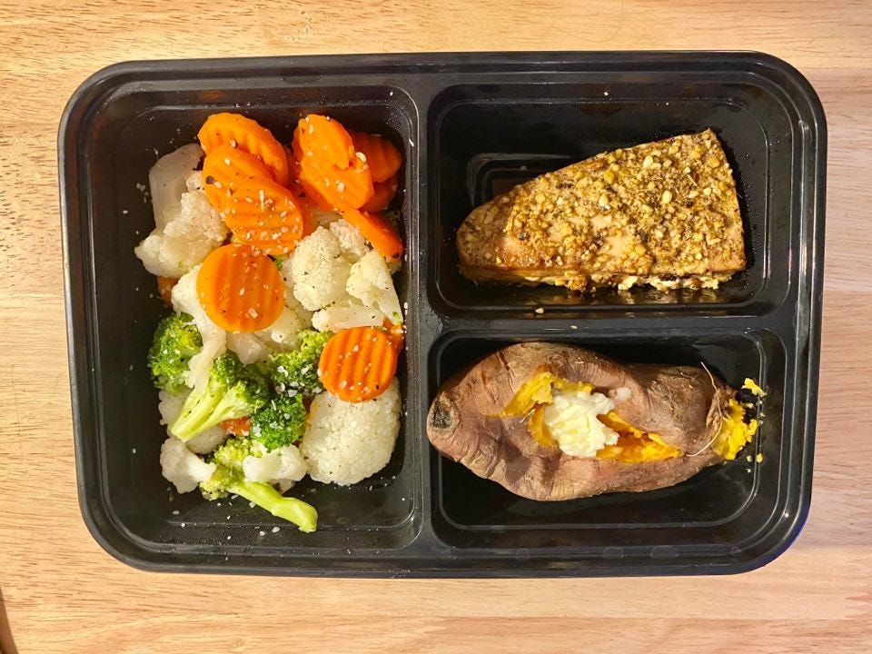 A meal prepped container with veggies, tuna, and a sweet potato