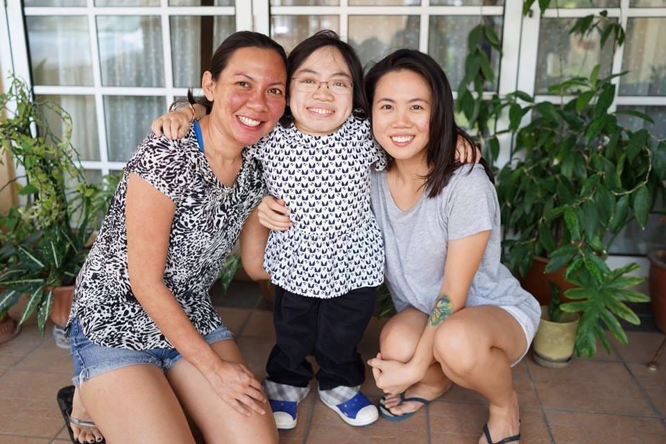 Rozella in denim shorts and patterned blouse and photographer Melissa Toh hugging Morquio Syndrome advocate, Rachel Siew