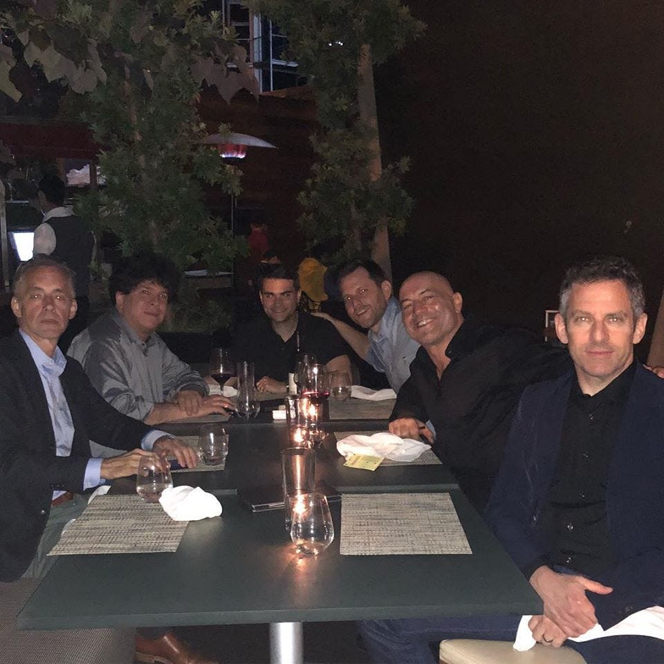 Jordan Peterson, Eric Weinstein, Ben Shapiro, Dave Rubin, Joe Rogan, and Sam Harris sitting at a table together in a dining or drinking establishment.