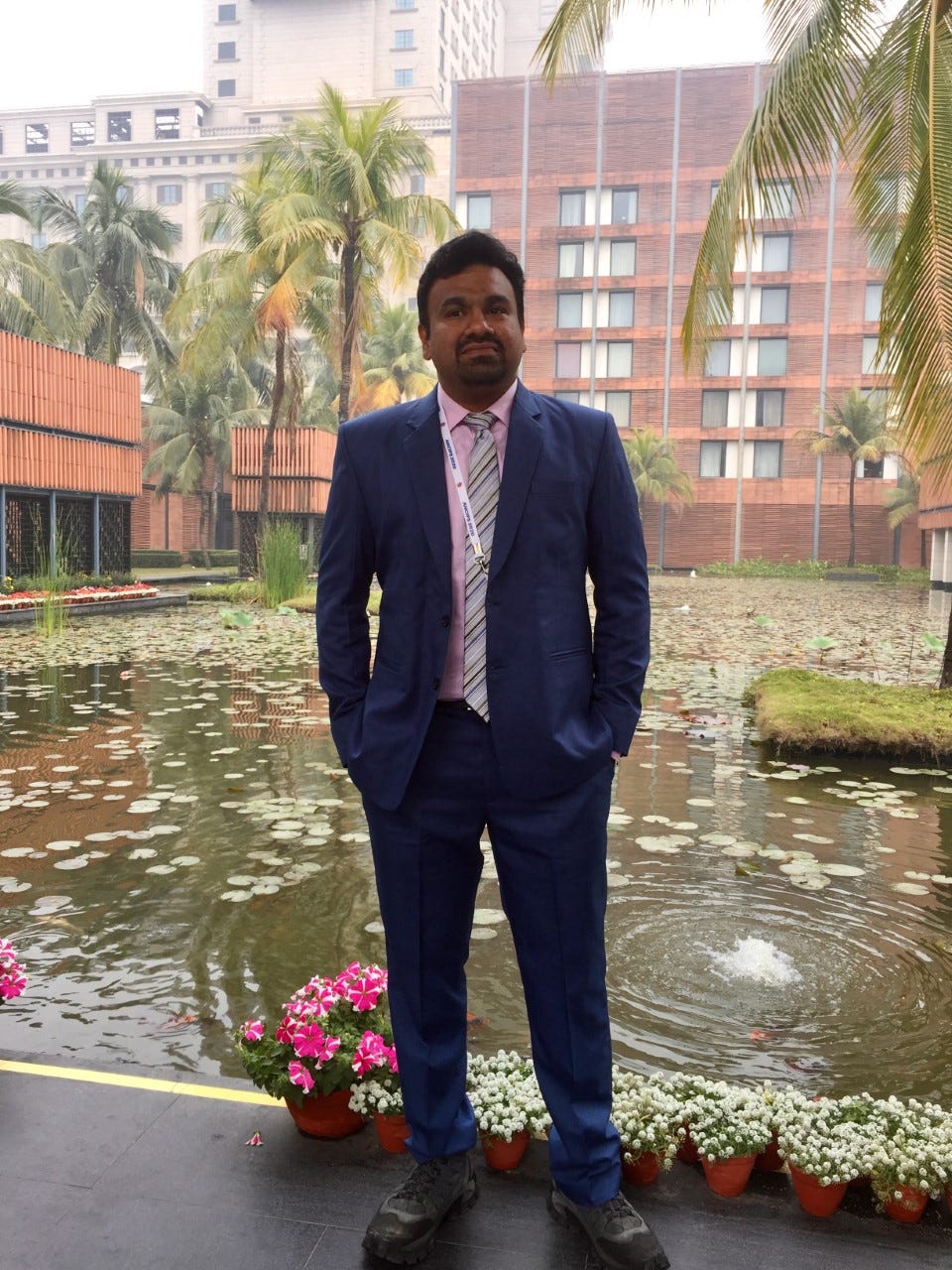 Dr. Sharad in a dark bule suit standing in front of a pool