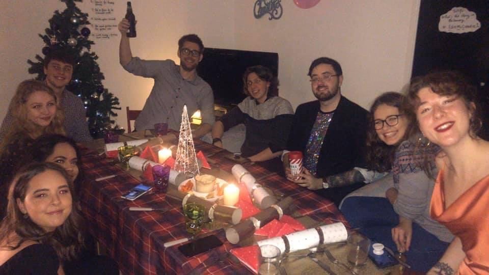 Big group of friends sharing a Christmas meal together around a table