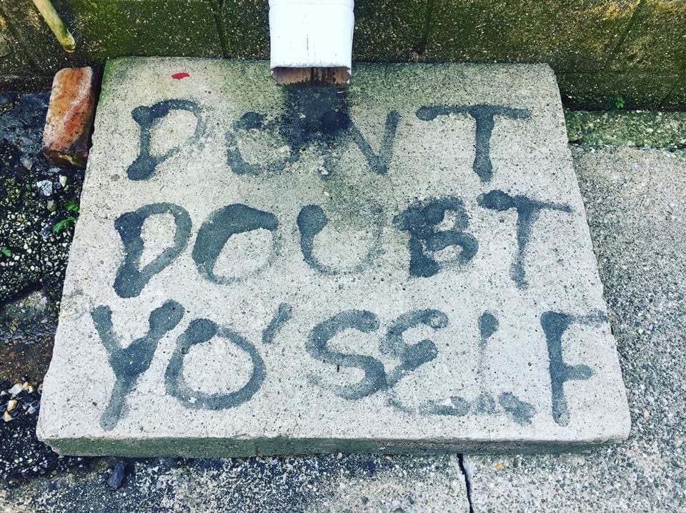 The words “don’t doubt yo’self” are spray-painted in black on cement.