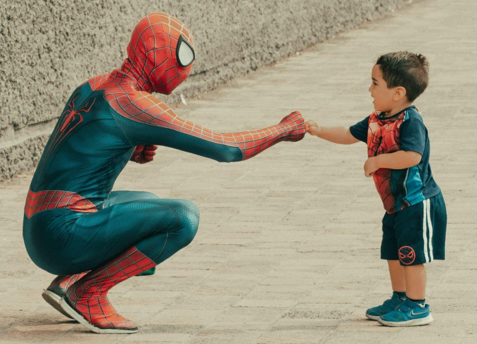 A Man in Spiderman Costume Doing Fist Bump on a Young Boy