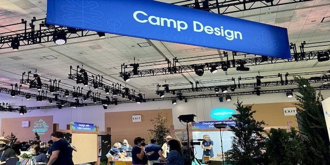 Wide shot of the Camp Design “booth” during TDX at Moscone Center. A large blue Camp Design banner hangs from the ceiling.