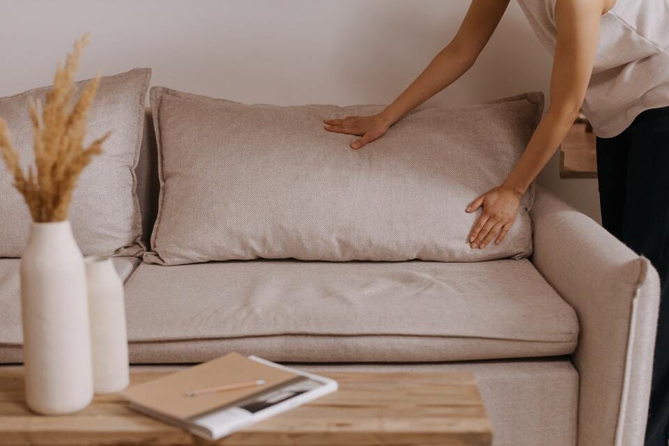 A person setting the living room sofa cushions to organize home.