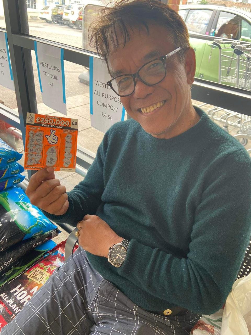 My father, smiling, and holding up a scratch off lottery ticket that won him five quid.