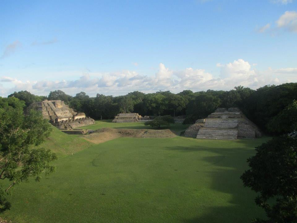 Open grassy field flanked by three ancient Mayan structures.