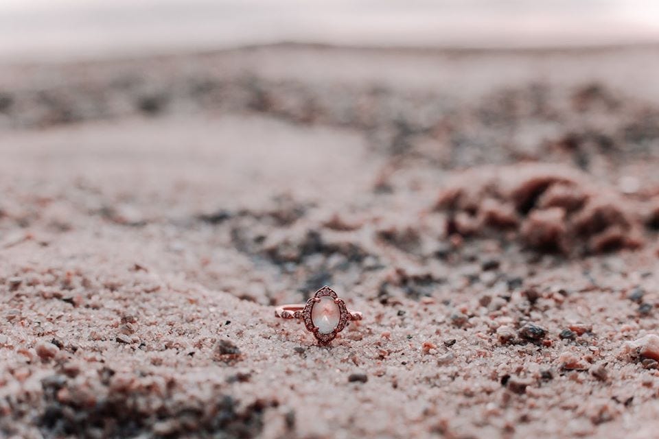 Engagement ring in the sand by Wildly Wed