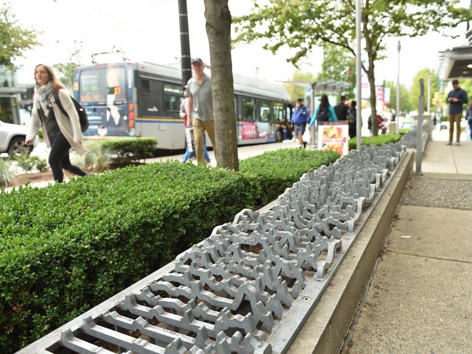 A metal grate art installation that spikes up and down is attached along a ledge to prevent and sitting