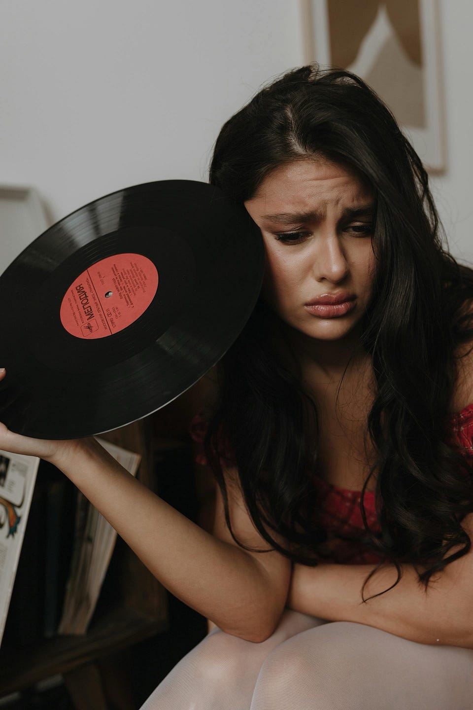 Woman holding vinyl record album, looking sad