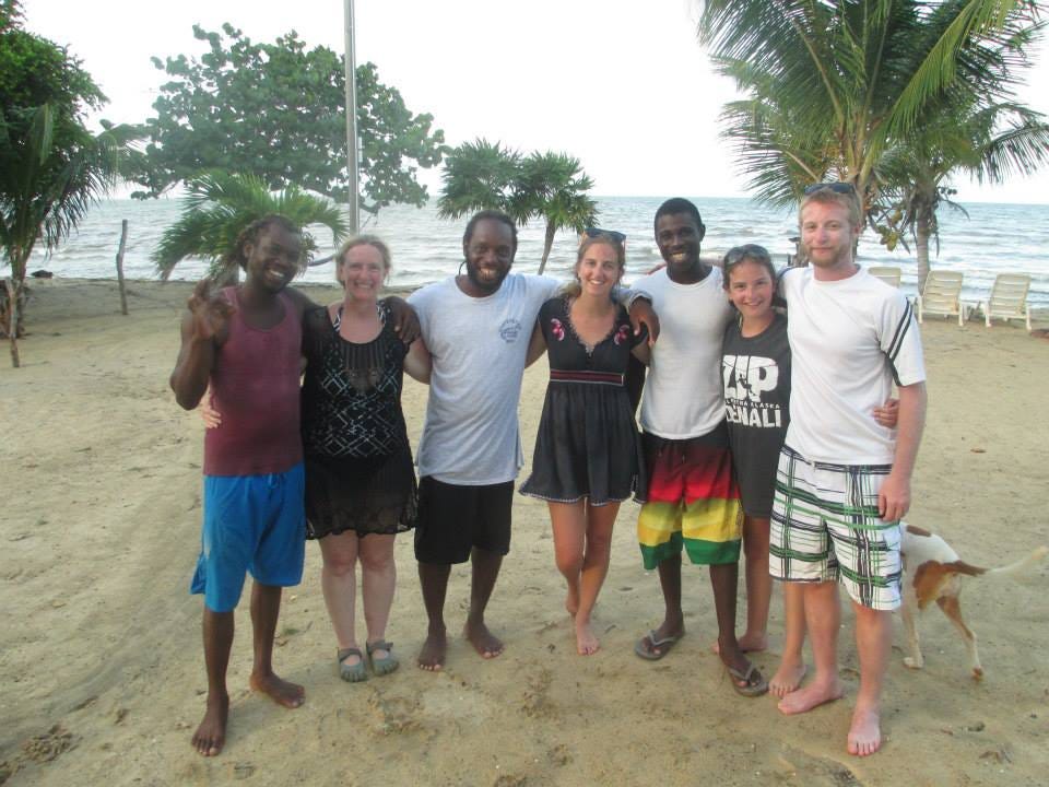 The author with her family standing side by side with three black gentlemen, arms around one another on a sandy beach as they smile for the camera.