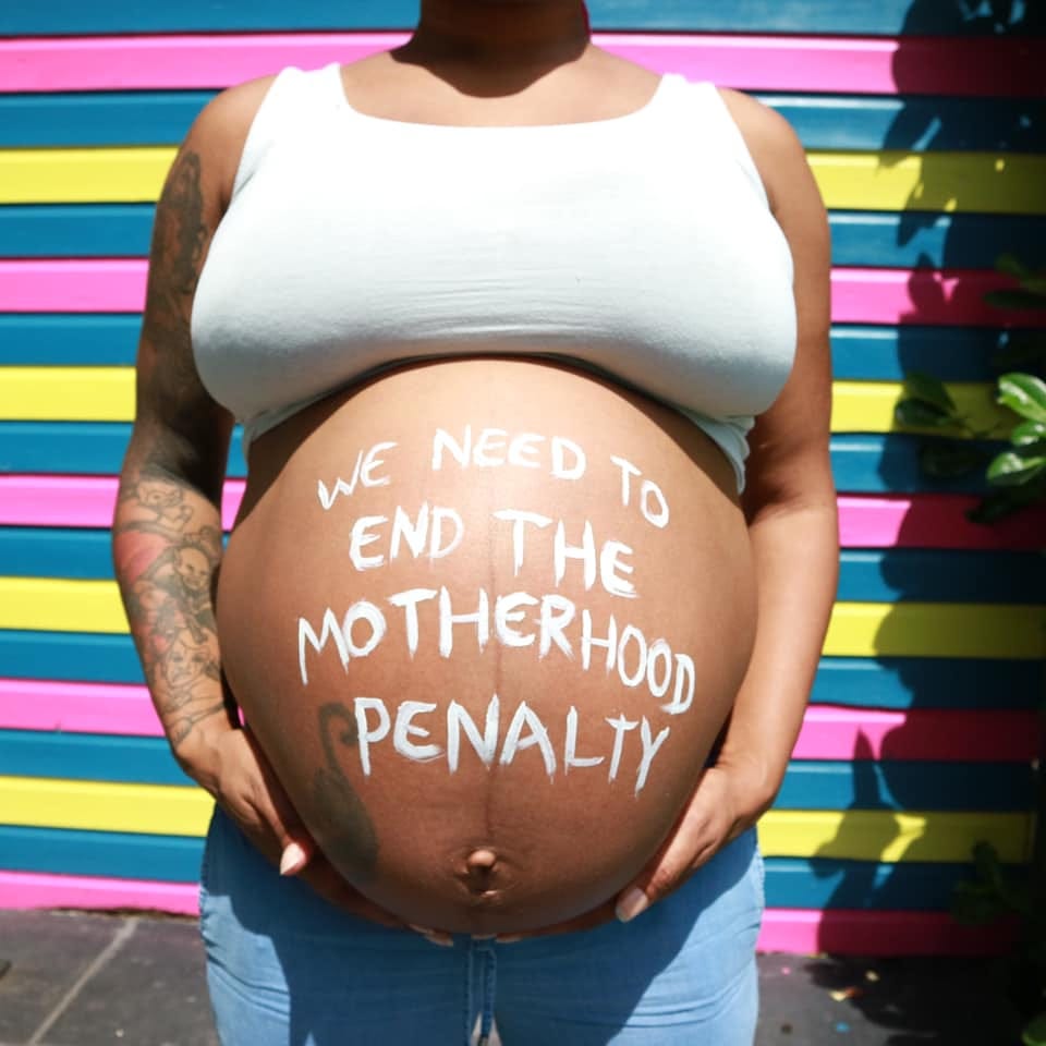 Pregnant bump stating ‘we need to end the motherhood penalty’