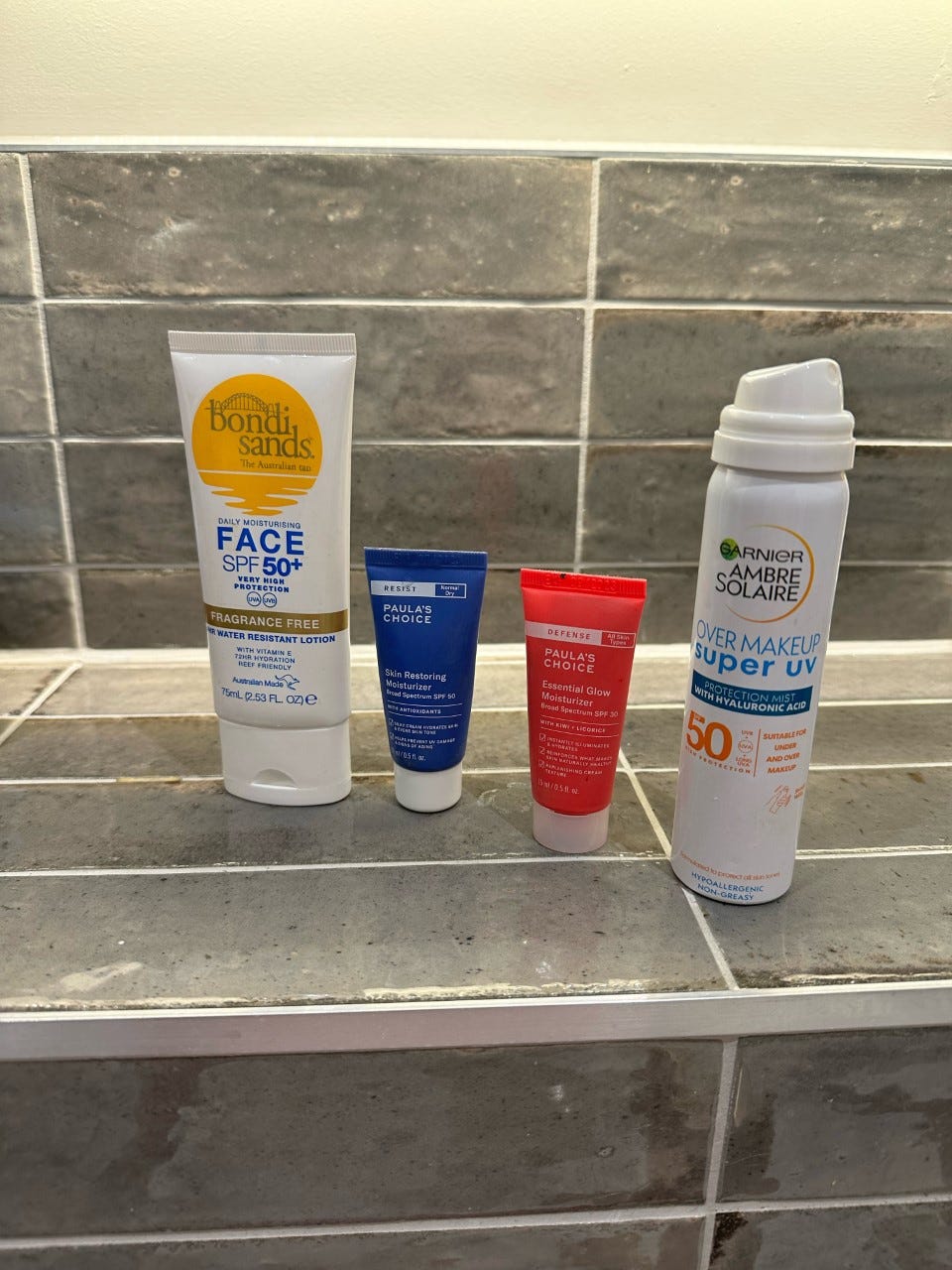 Image of four bottles of SPF on a bathroom countertop