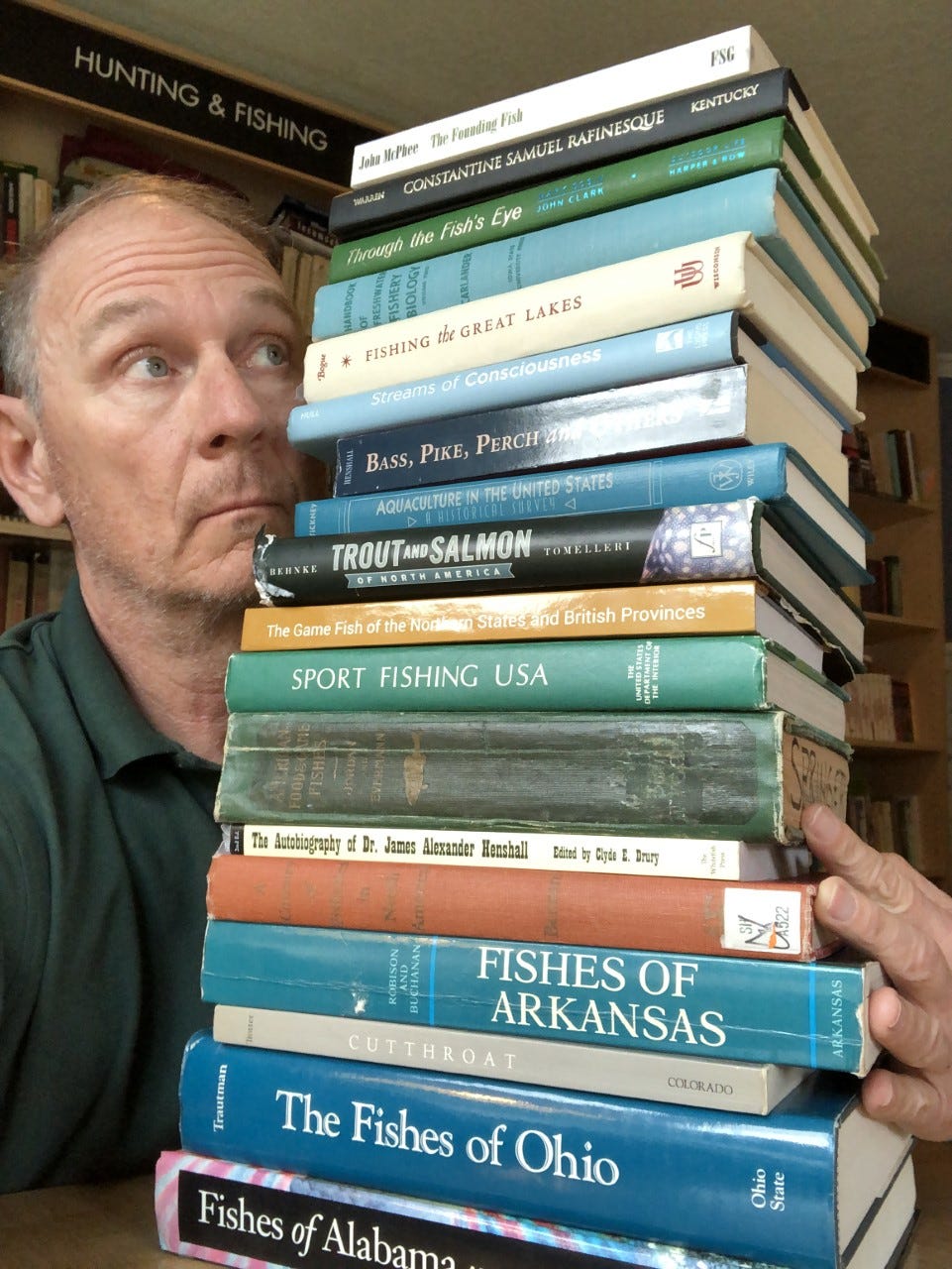 Craig Springer holding a stack of books in hand.