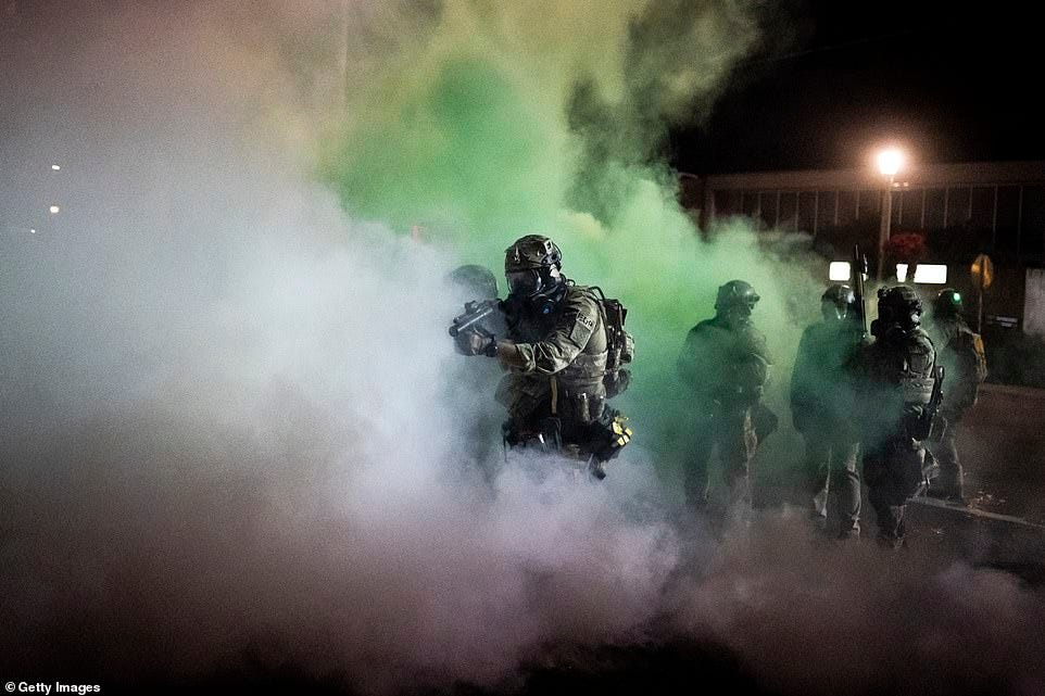 Federal agents with launching weapons amid a cloud of green fog