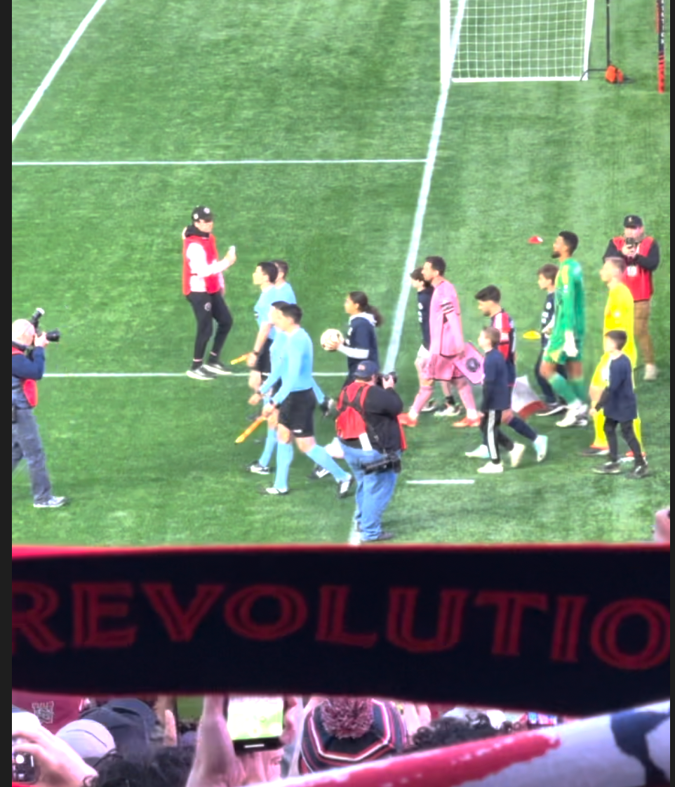 MLS referee crew, Carles Gil of New England Revolution, and Lionel Messi, the greatest soccer player on the planet, taking the field at Gillette Stadium on April 27, 2024. Gil in the Revs blue kits with red accents, Messi in the Inter Miami pink kit.