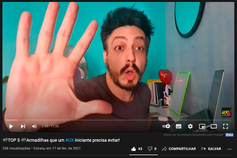 Frame do video mencionado no qual eu estou com cara de surpresa mostrando para a câmera um número 5 feito com os dedos