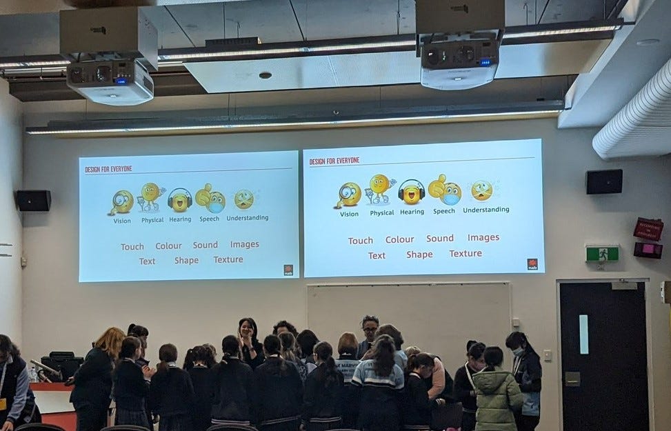 NAB staff talking with students in a room in front of a slideshow presentation being displayed behind them.